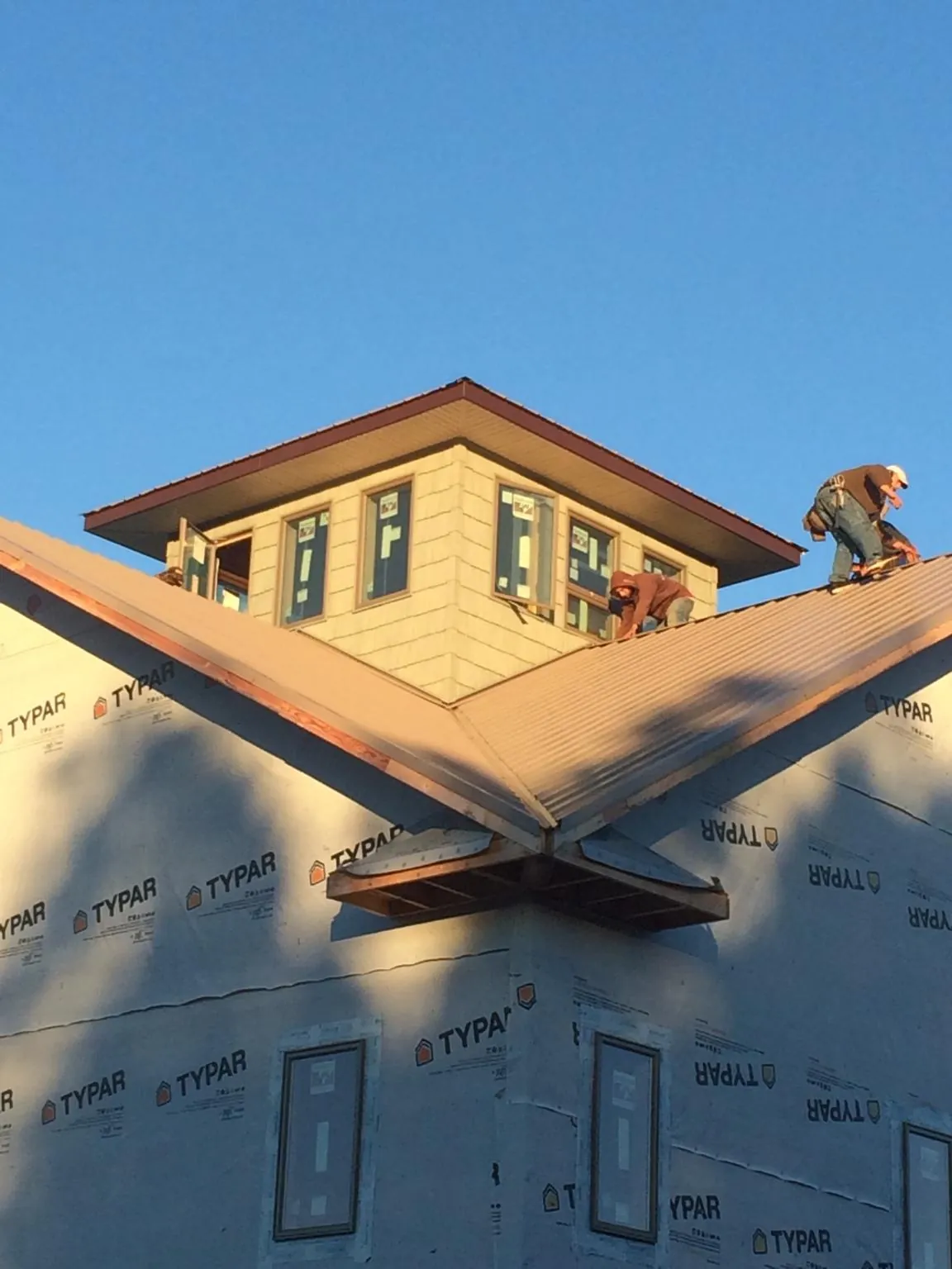 Roofers working around a rooftop cupola on a new metal roof at sunset — Roof Waterproofing in Burbank by Roofing Brothers